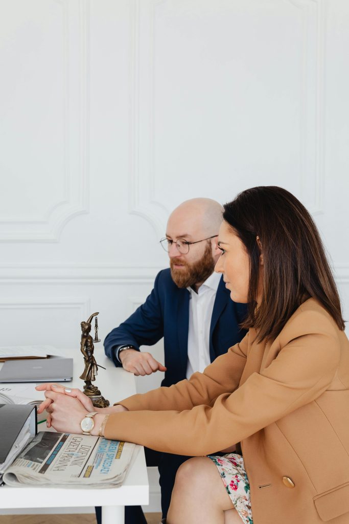 Man and woman discussing legal documents indoors, featuring Lady Justice statue.